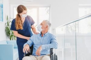 young,woman,nurse,explaining,information,to,man,patient,in,wheelchair